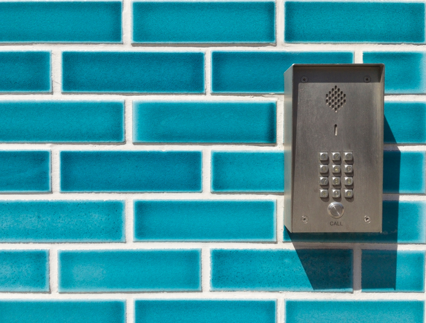 Picture of a telephone line intercom system using a phone line to call residents of a building, mounter outside a decorative facade, showing a typical phone entry intercom system,